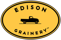 Edison Grainery Logo - a stamped image of a vintage black truck centered on a golden yellow oval, framed above and below by the words EDISON GRAINERY TM