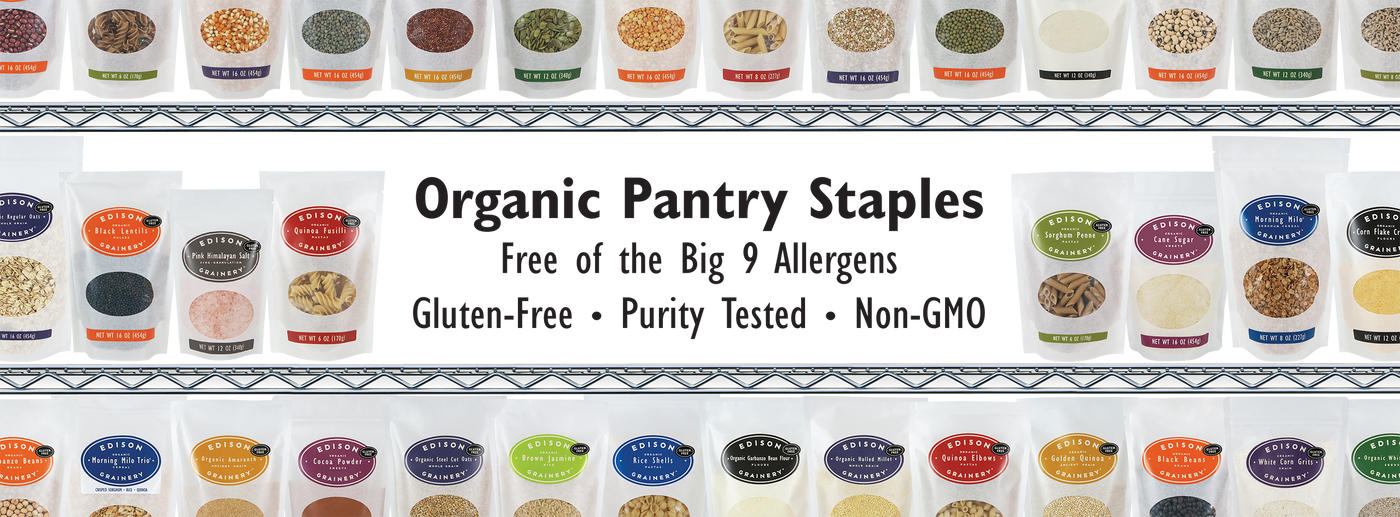 A wide angle photo of EDISON GRAINERY products lined up on a grocery shelf. In an open space at the center of the image are the words: "Organic Pantry Staples - Free of the Big 9 Allergens - Gluten-Free - Purity Tested - Non-GOM".