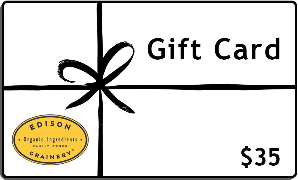 A white rectangular gift wrapped in a black ribbon with the words Gift Card, $35 and a golden yellow logo superimposed atop it.
