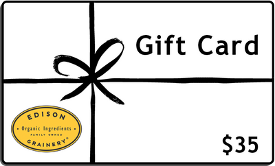 A white rectangular gift wrapped in a black ribbon with the words Gift Card, $35 and a golden yellow logo superimposed atop it.