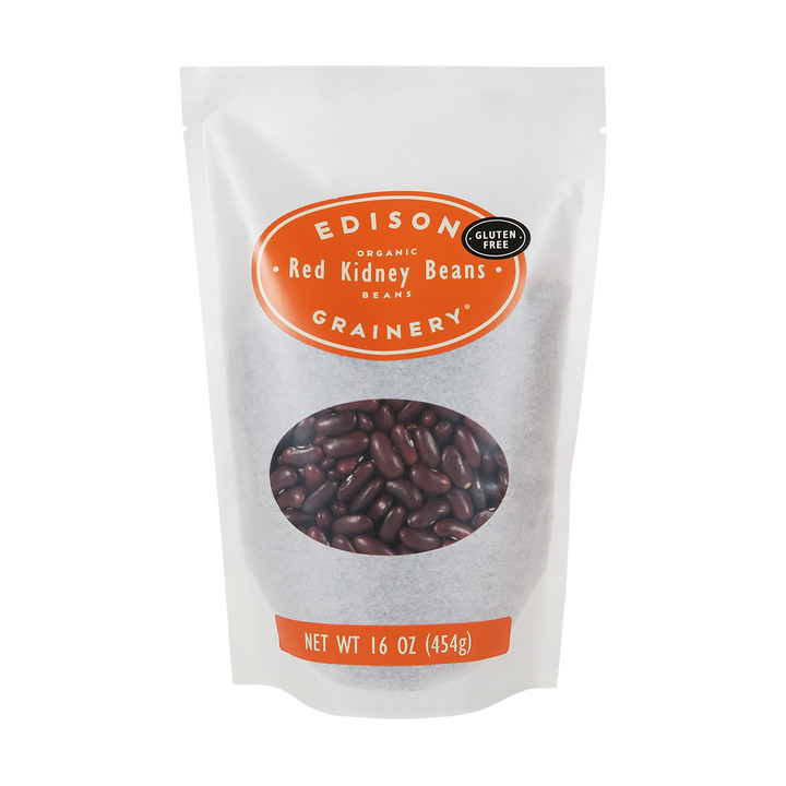 A 16 oz bag of Organic Dark Red Kidney Beans standing upright in a bio-degradable bag. An orange oval label, bearing the product name sits above an oval viewing window revealing the product.