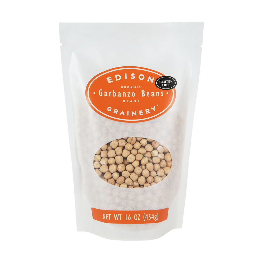 A 16 oz bag of Organic Garbanzo Beans standing upright in a bio-degradable bag. An orange oval label, bearing the product name sits above an oval viewing window revealing the product.