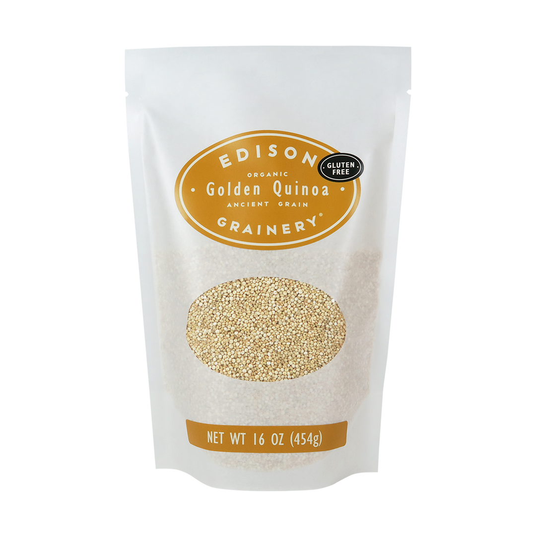 A 16 oz bag of Organic Golden Quinoa standing upright in a bio-degradable bag. A golden yellow oval label, bearing the product name sits above an oval viewing window revealing the product.