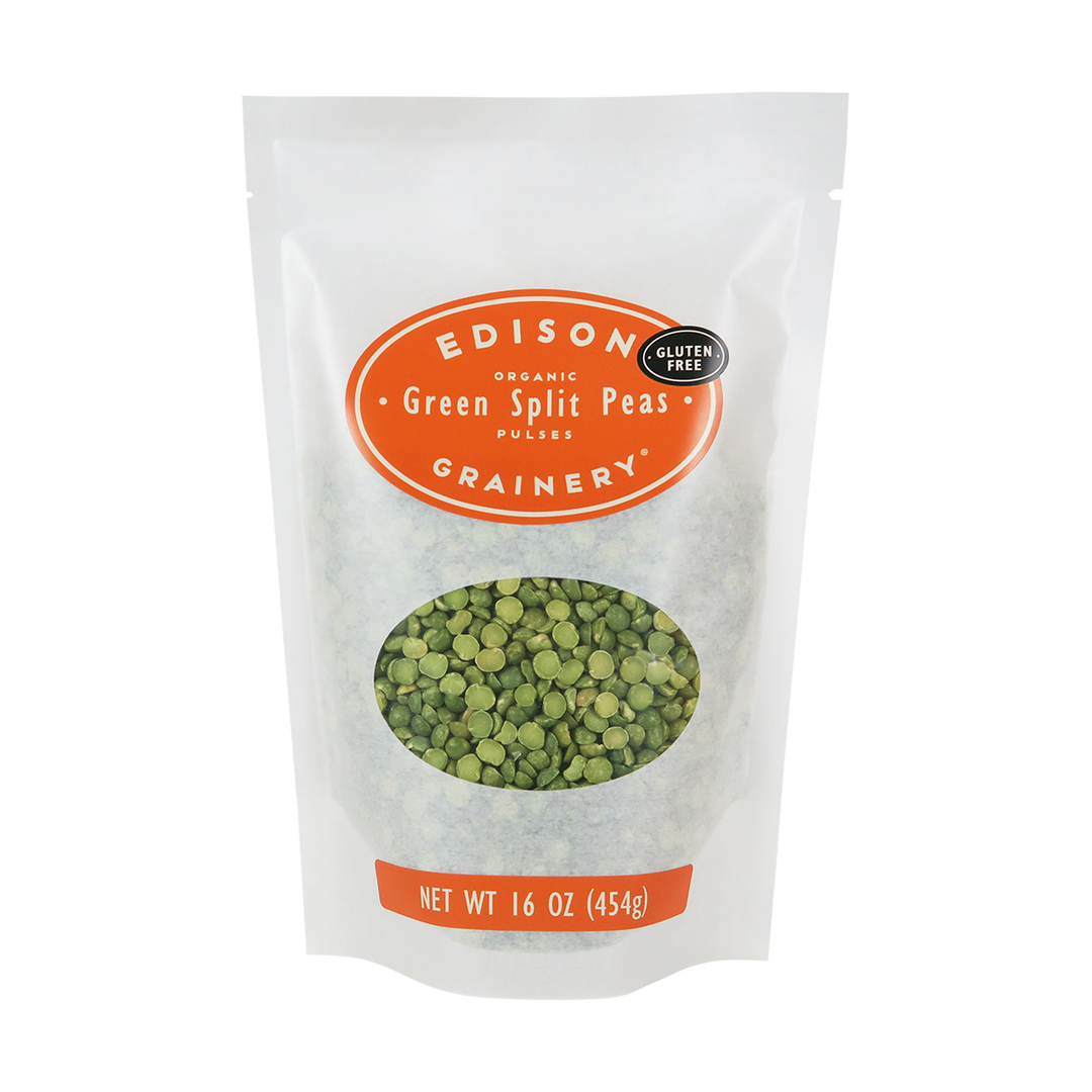 A 16 oz bag of Organic Green Split Peas standing upright in a bio-degradable bag. An orange oval label, bearing the product name sits above an oval viewing window revealing the product.