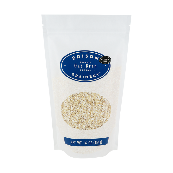 A 16 oz bag of Organic Oat Bran standing upright in a bio-degradable bag. A royal blue oval label, bearing the product name sits above an oval viewing window revealing the product.