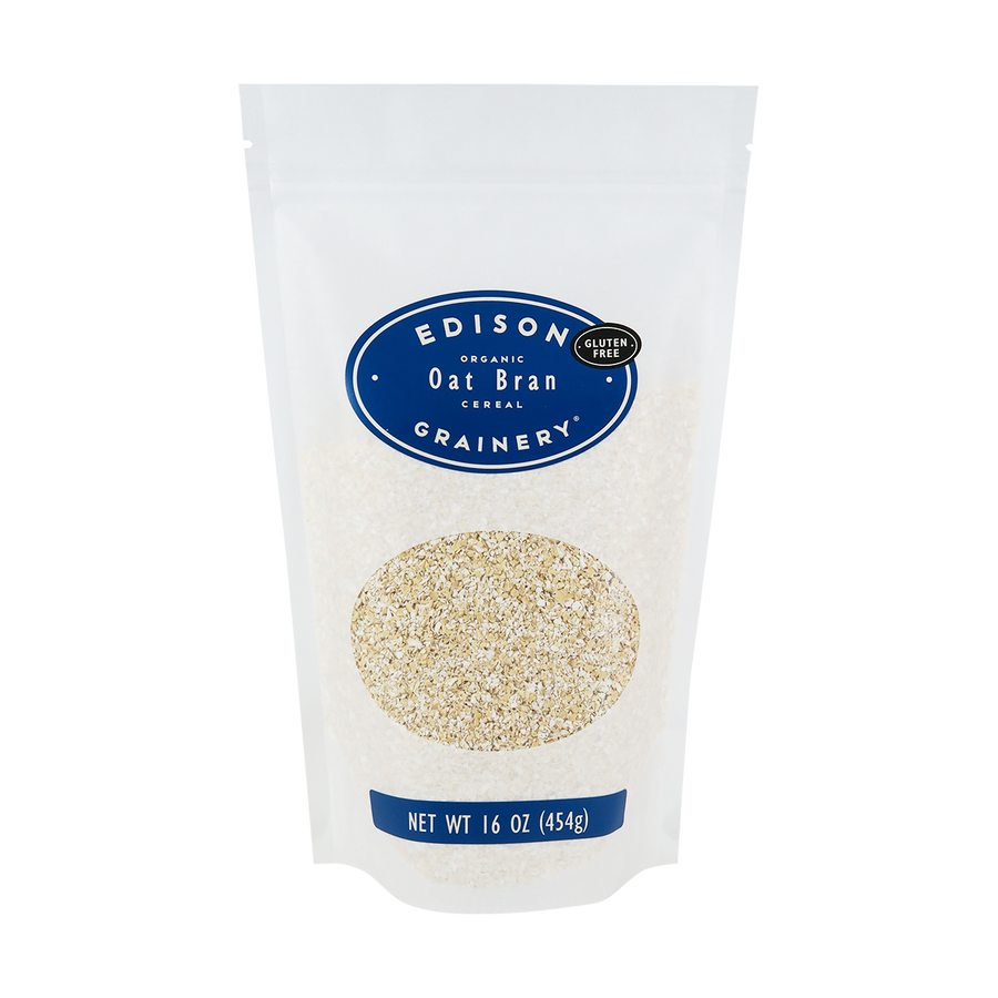 A 16 oz bag of Organic Oat Bran standing upright in a bio-degradable bag. A royal blue oval label, bearing the product name sits above an oval viewing window revealing the product.