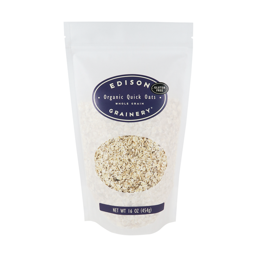 A 16 oz bag of Organic Quick Oats standing upright in a bio-degradable bag. A deep purple oval label, bearing the product name sits above an oval viewing window revealing the product.