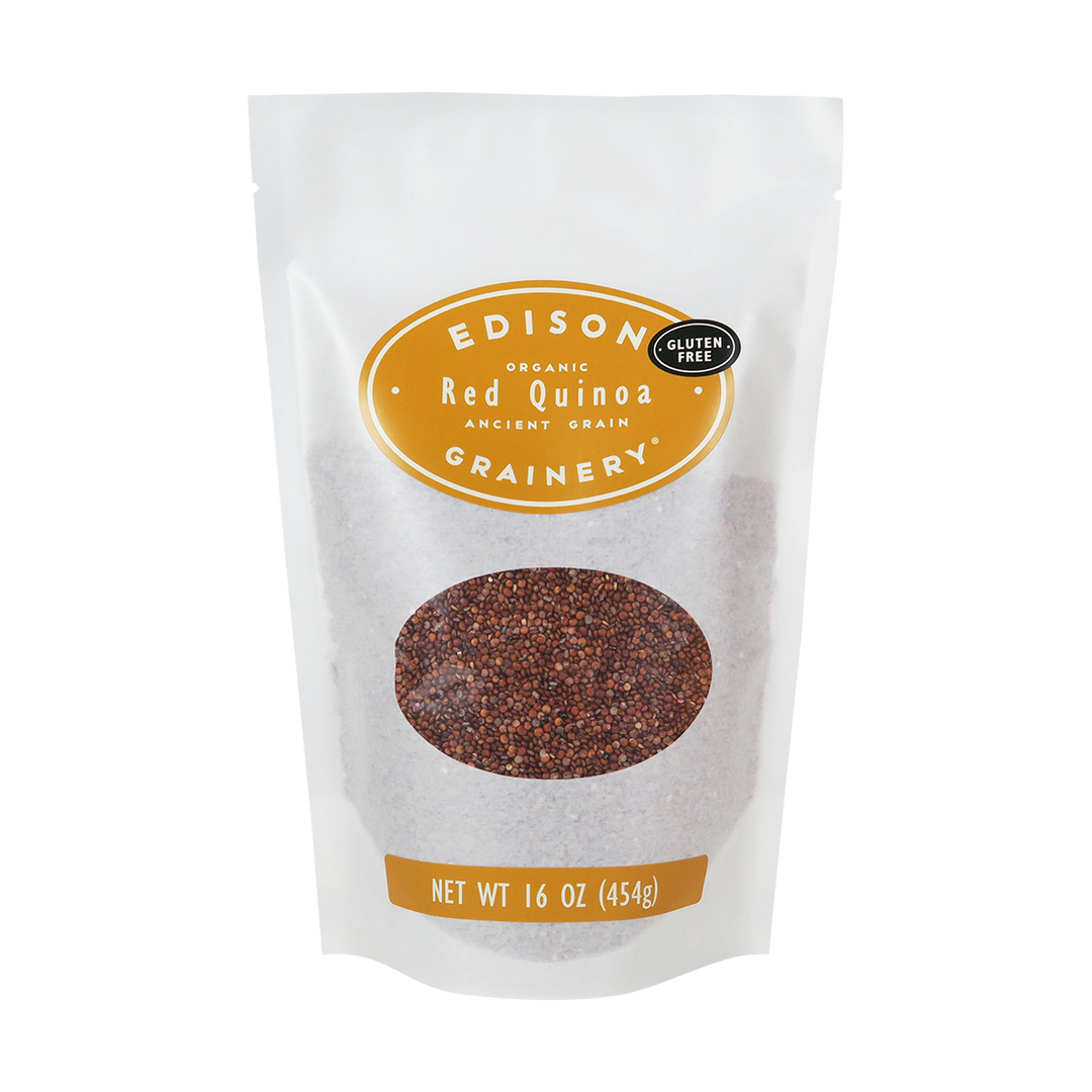 A 16 oz bag of Organic Red Quinoa standing upright in a bio-degradable bag. A golden yellow oval label, bearing the product name sits above an oval viewing window revealing the product.