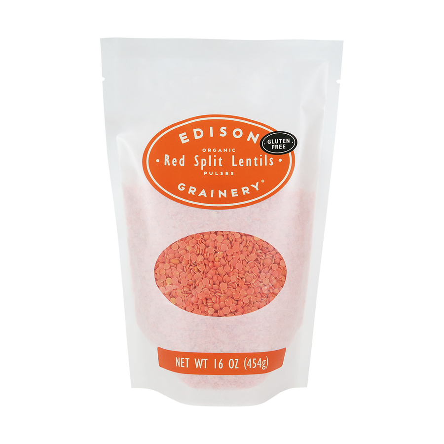 A 16 oz bag of Organic Red Split Lentils standing upright in a bio-degradable bag. An orange oval label, bearing the product name sits above an oval viewing window revealing the product.