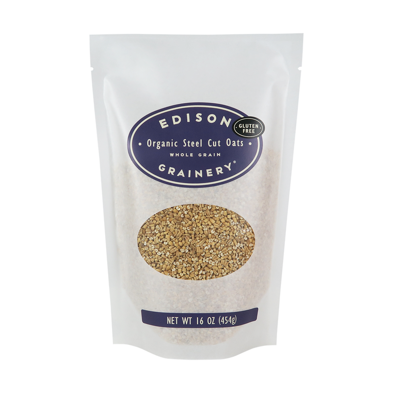 A 16 oz bag of Organic Steel Cut Oats standing upright in a bio-degradable bag. A deep purple oval label, bearing the product name sits above an oval viewing window revealing the product.