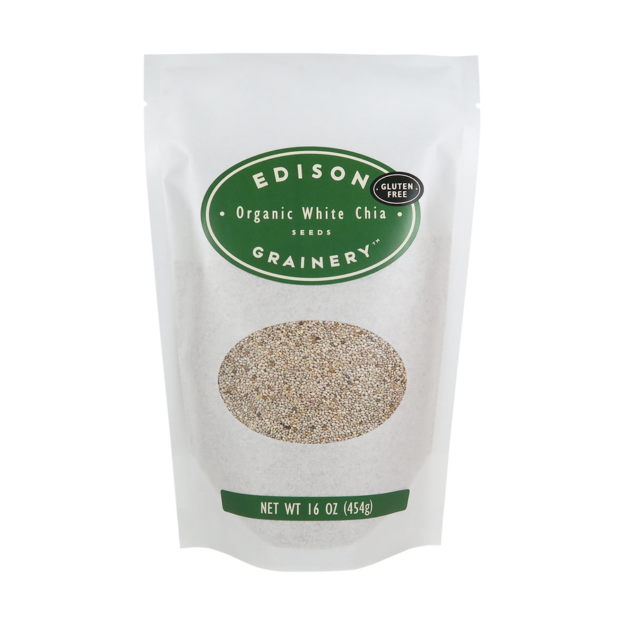 A 16 oz bag of Organic White Chia Seeds standing upright in a bio-degradable bag. A forest green oval label, bearing the product name sits above an oval viewing window revealing the product.